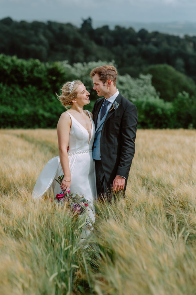 A bride and groom standing in a wheat field.