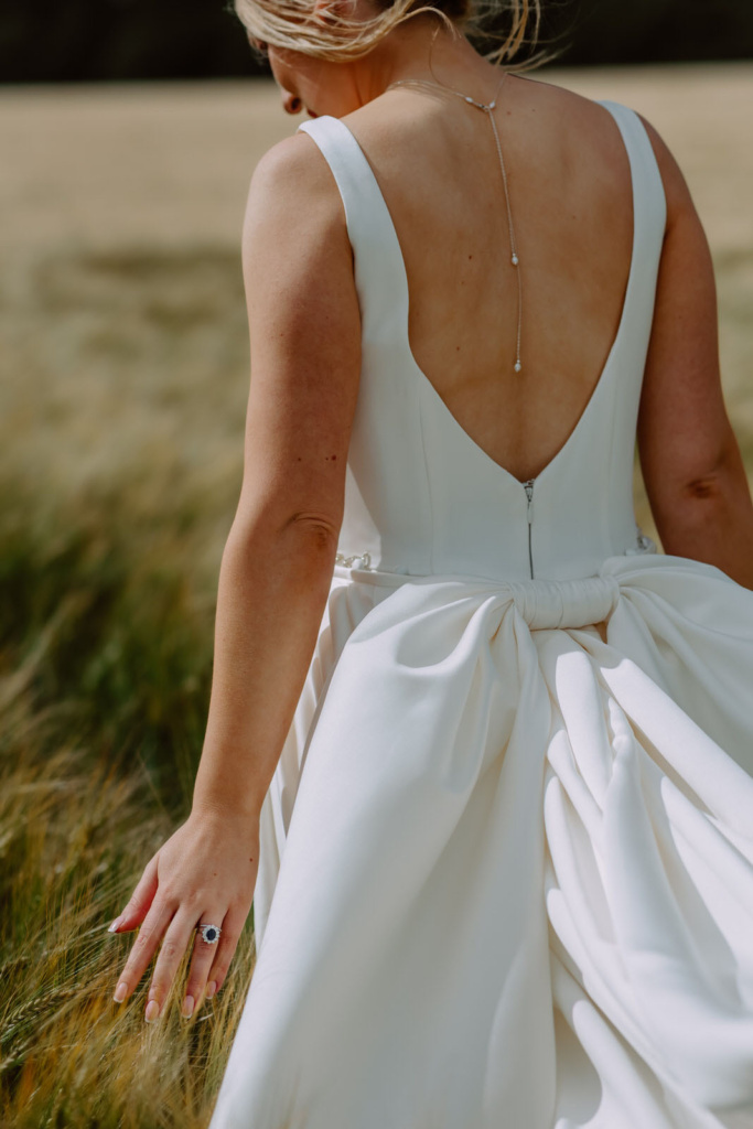 A bride in a white wedding dress walking through a field.