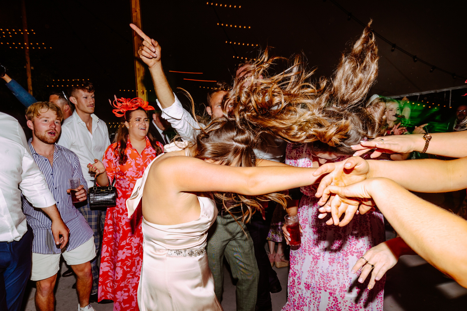 A woman dancing with her hair in the air at a party at Warwickshire farm.