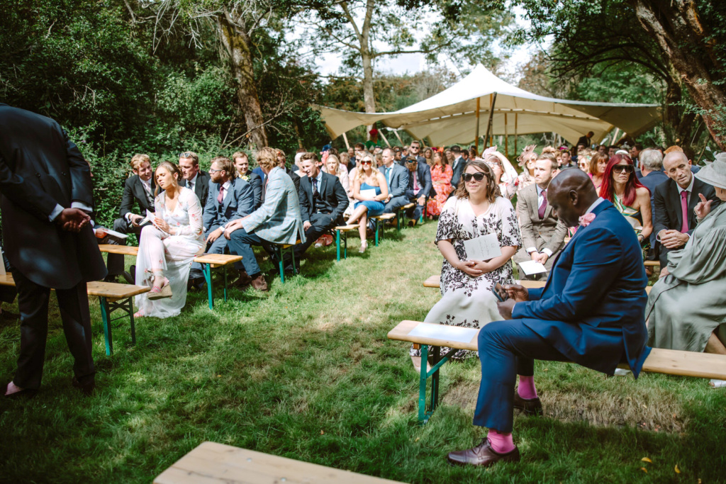 A wedding ceremony in a garden with people sitting on benches.