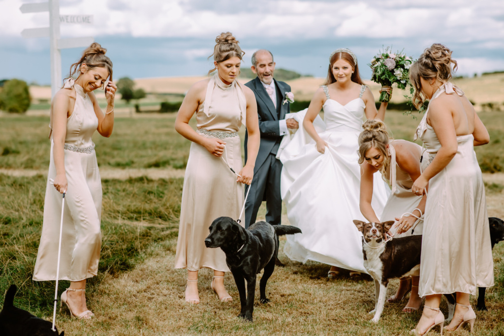 A group of bridesmaids and their dog in a field.