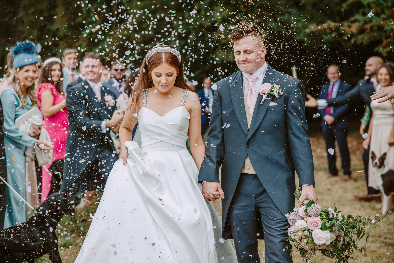 A bride and groom walk down the aisle with confetti thrown at them.