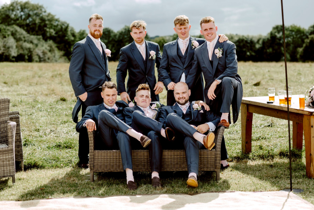 A group of groomsmen in suits posing for a photo.
