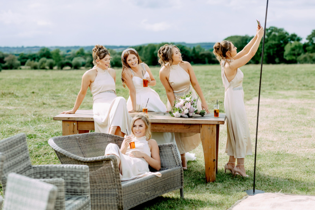 A group of bridesmaids taking a selfie in a field.