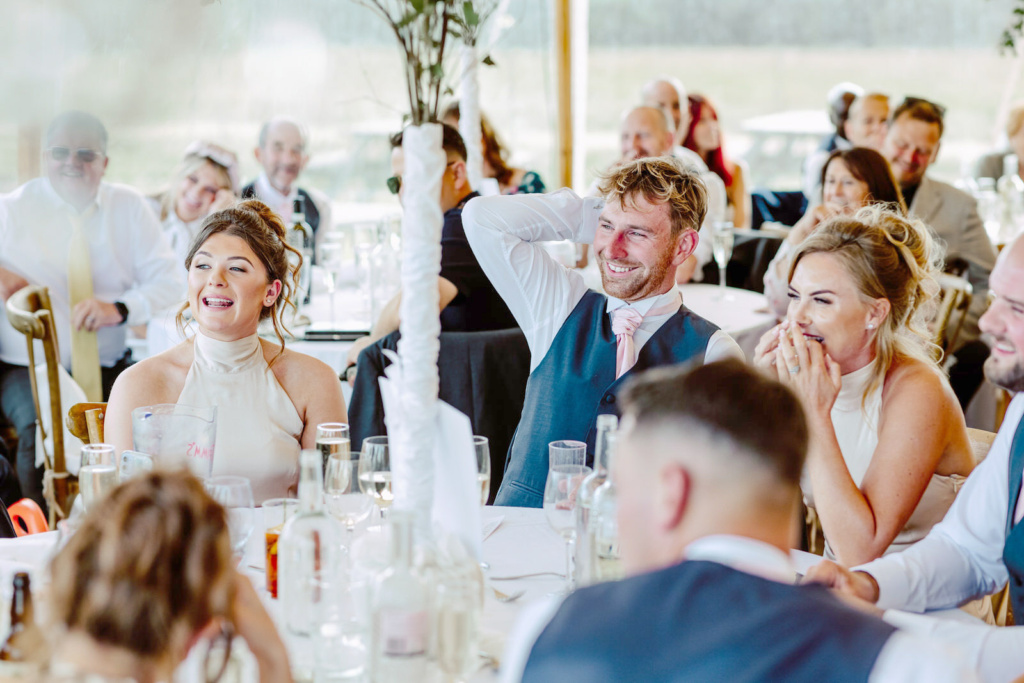 A group of people laughing at a wedding reception.