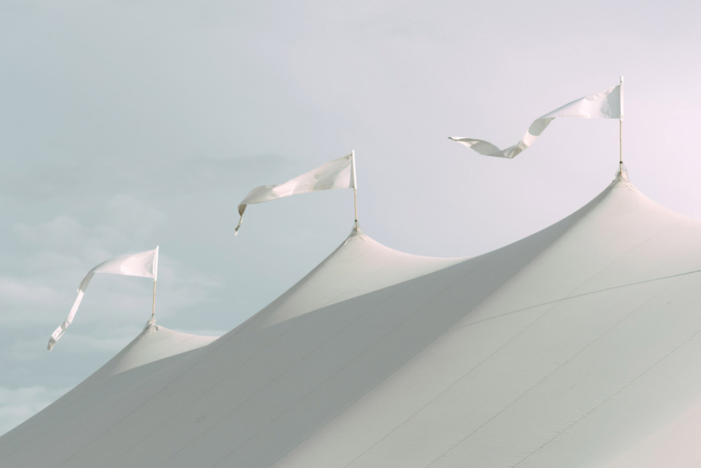White flags flying from the top of a white marquee.