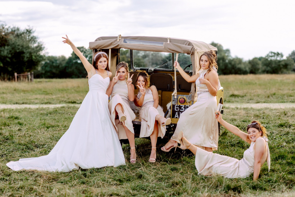 A group of bridesmaids posing in front of a jeep in warwickshire farm wedding.