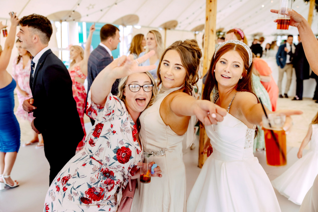 A group of bride and bridesmaids dancing in a marquee.