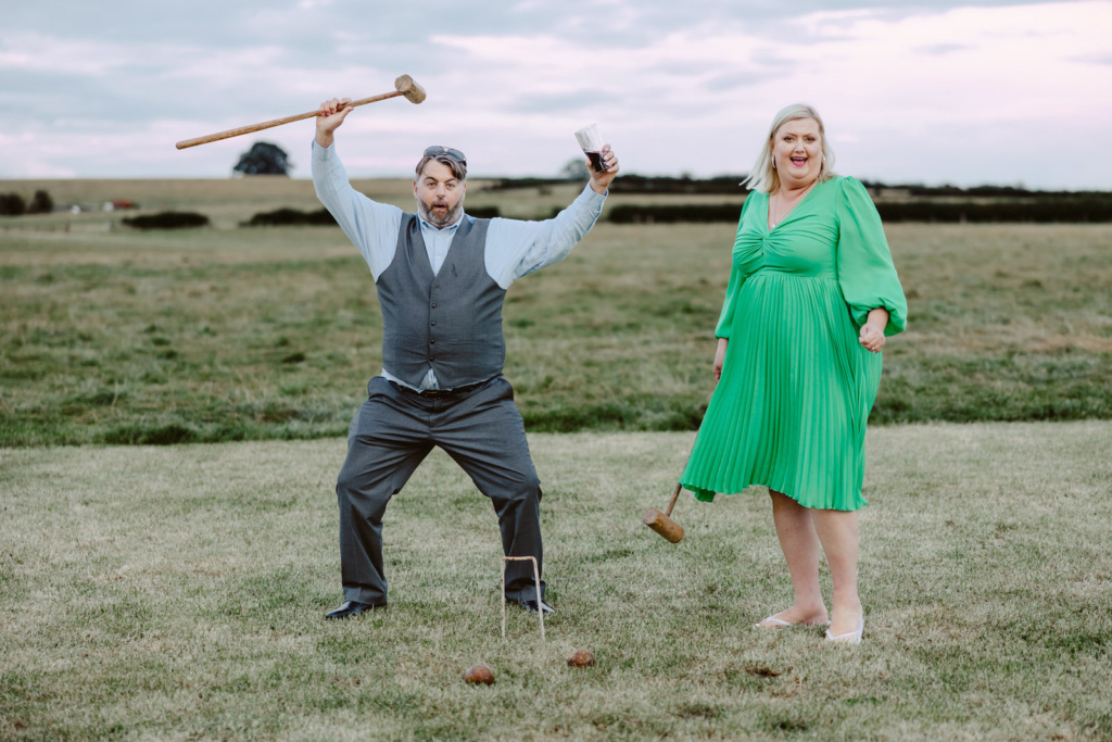 A man and woman playing croquet in a field.