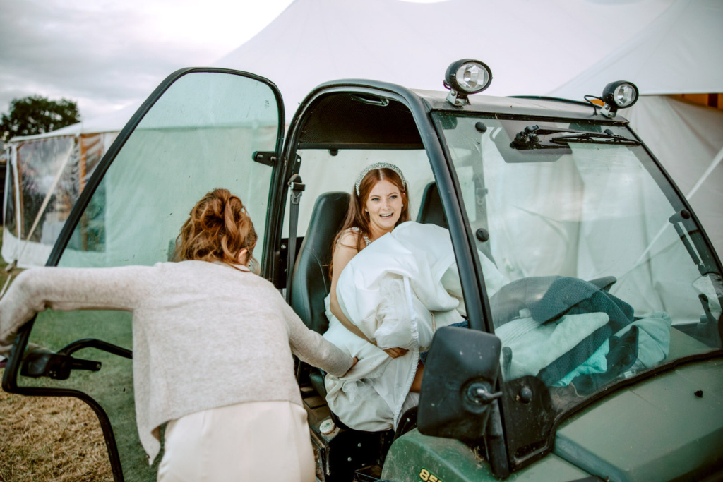 A bride is getting into the back of a terrain car.