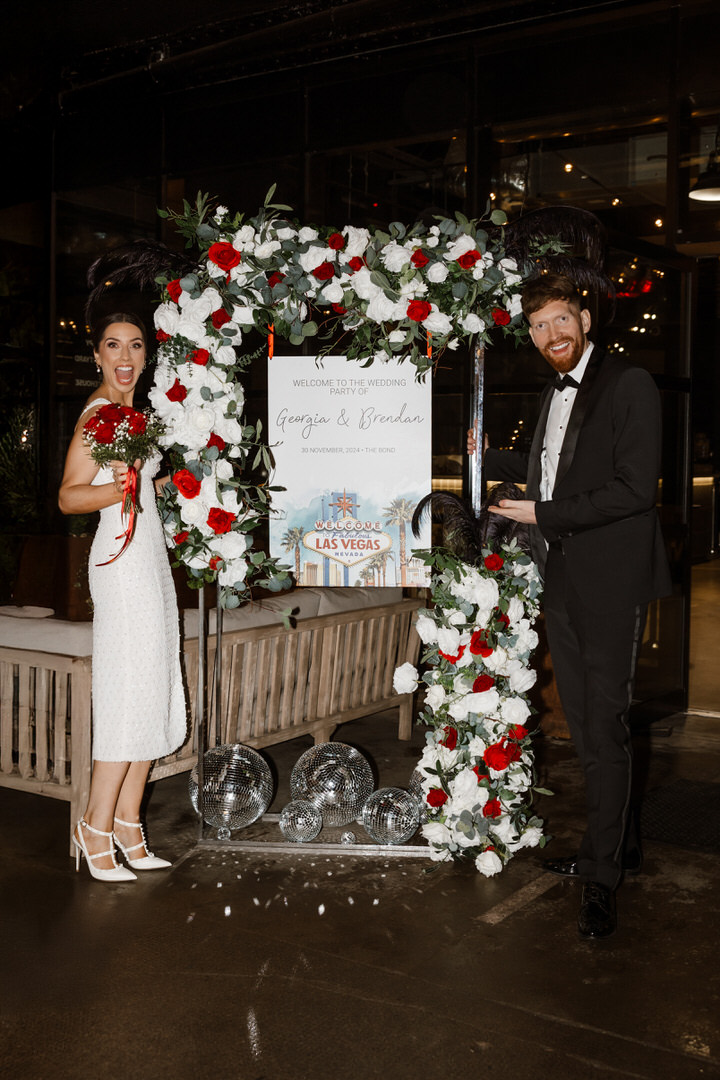 The bride and the groom posing next to their wedding sign