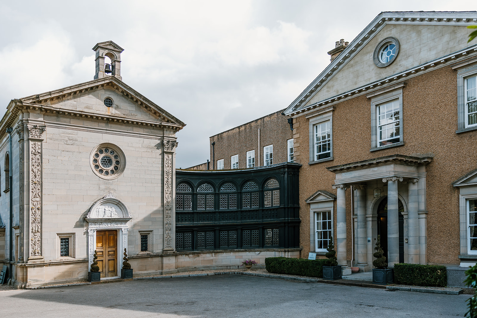 The Chapel and Bourton Hall entrance feature two historic buildings with classical architecture, including columns and decorative stonework, connected by a black enclosed walkway.